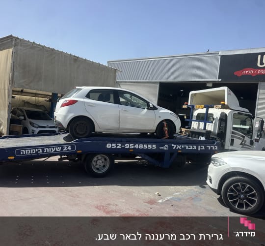 גרר עם רכב לבן על משאית גרירה בחניון